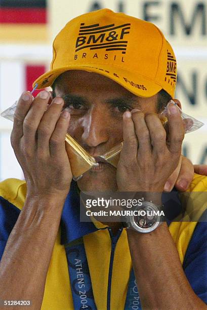 Vanderlei Cordeiro de Lima, Brazilian marathon runner and bronze medalist in Athens, kisses his two gold ingots given by his sponsor, the Futures and...