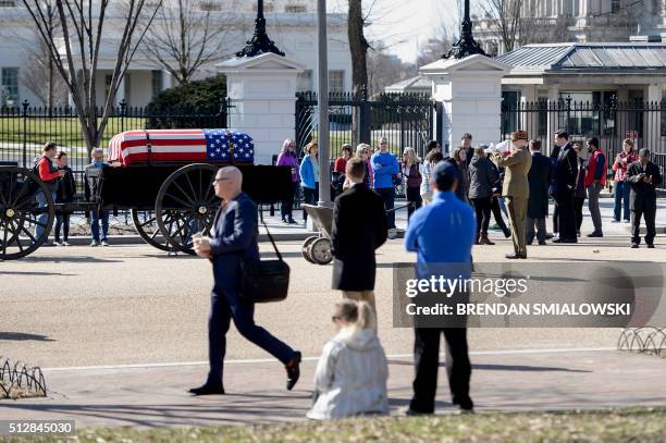 Tourists look at a flag draped casket on a caisson outside the White House during the filming a scene for the movie 'Jackie' on Pennsylvania Avenue...