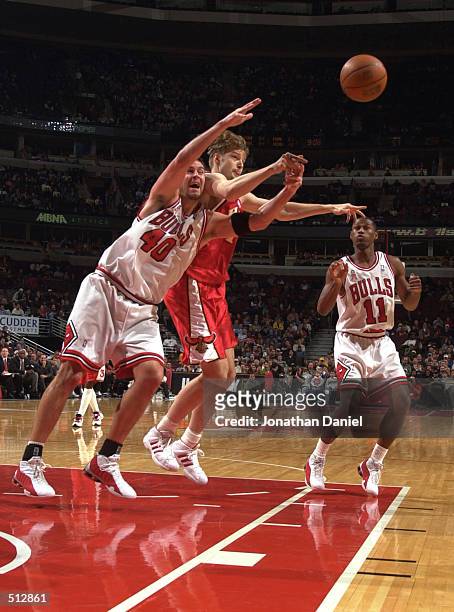 Center Brad Miller of the Chicago Bulls collides with forward Hanno Mottola of the Atlanta Hawks while chasing the ball as guard A.J. Guyton watches...