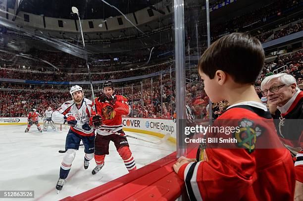 Young fan watches Brooks Laich of the Washington Capitals and Richard Panik of the Chicago Blackhawks during the NHL game at the United Center on...