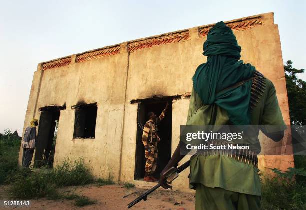 Sudanese rebel from the Justice and Equality Movement , investigates the scene in Ulang, a village recently burned by Janjaweed militiamen in the...