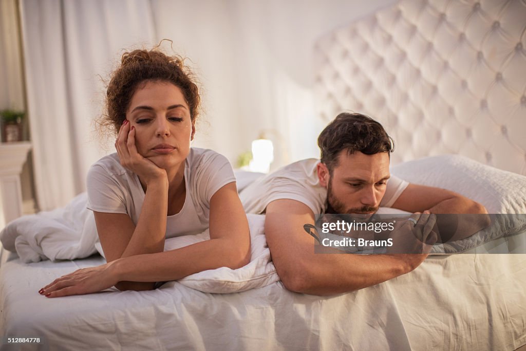 Depressed couple having relationship problems in their bed.