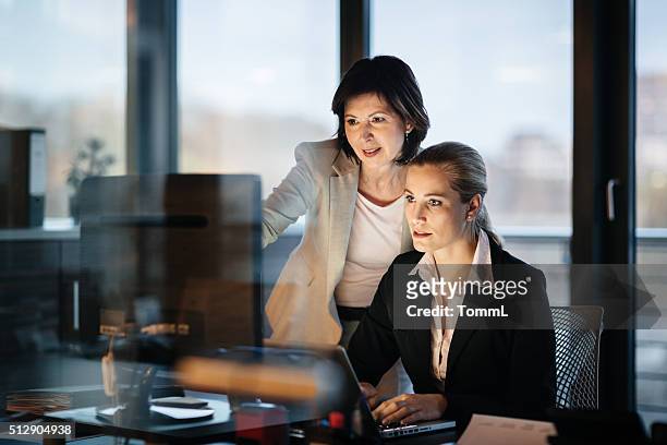young and mature business woman working late - leadership coaching stock pictures, royalty-free photos & images