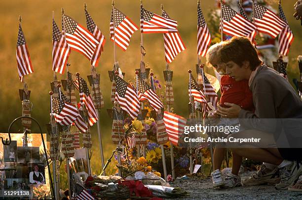 Mother holds her daughter as the sun sets behind them at the temporary memorial for the crash of Flight 93 on September 11, 2004 near Shankville,...