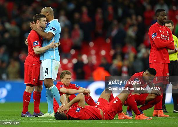 Vincent Kompany of Manchester City hugs James Milner of Liverpool as the Liverpool team sit dejected after the Capital One Cup Final match between...