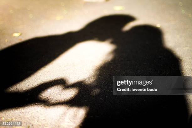 silhouette of two lovers. kissing and forming a heart shape. - man desire stock pictures, royalty-free photos & images