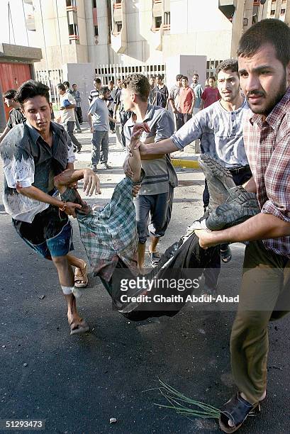 Iraqi civilians carry an injured man during fighting on September 12, 2004 in Haifa Street, Baghdad, Iraq. Fighting broke out in the early hours of...
