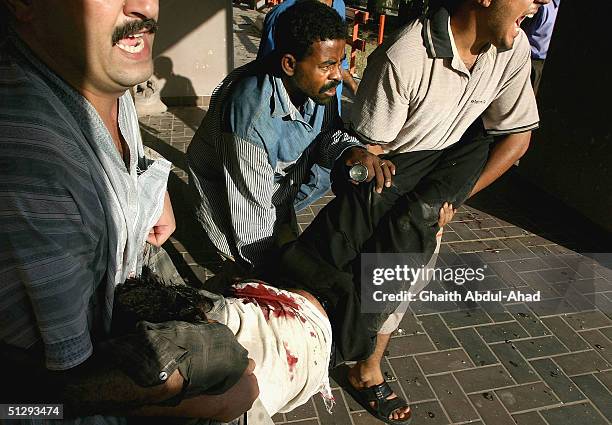 Iraqi civilians carry an injured man during fighting on September 12, 2004 in Haifa Street, Baghdad, Iraq. Fighting broke out in the early hours of...