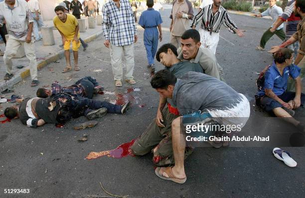 Iraqi civilians carry an injured man as other dead and injured people lie in the street on September 12, 2004 in Haifa Street, Baghdad, Iraq....