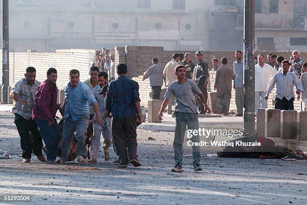 Iraqi civilians carry an injured man after clashes on September 12, 2004 in Haifa Street, Baghdad, Iraq. Fighting broke out in the early hours of...