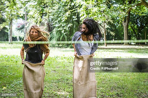two young woman having fun playing sack race - sack race stock pictures, royalty-free photos & images
