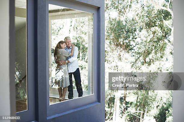 couple embracing while looking out through window - couple looking through window stock pictures, royalty-free photos & images