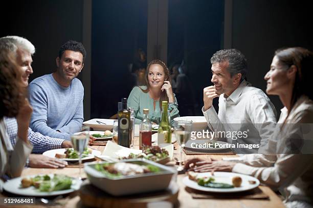 friends communicating while having dinner at table - cinque persone foto e immagini stock