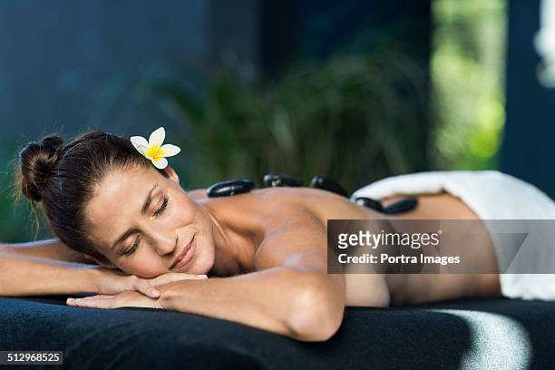 woman receiving hot stone therapy at a luxury spa. - halbbekleidet stock-fotos und bilder