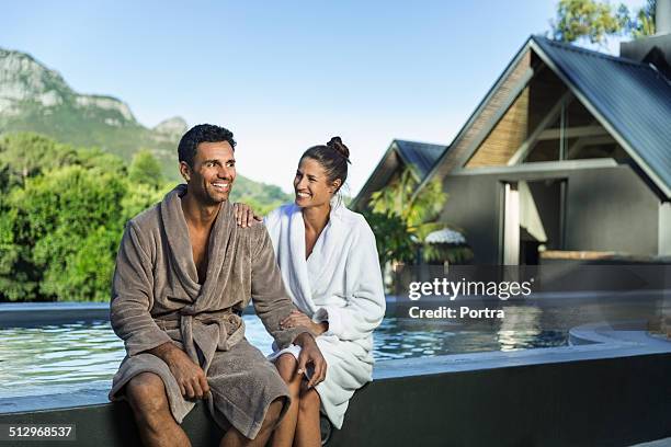couple in sitting at the edge of swimming pool - 40s couple sunny stock pictures, royalty-free photos & images