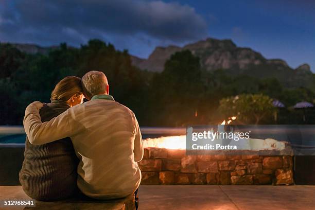 couple sitting in front of fire pit at night - sitting by fireplace stock pictures, royalty-free photos & images