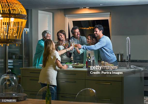 friends toasting drink glasses over kitchen island - party wohnzimmer stock-fotos und bilder