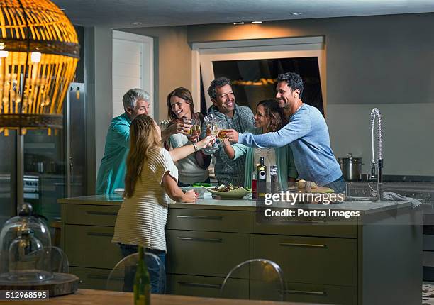 friends toasting drink glasses over kitchen island - celebrate living stockfoto's en -beelden