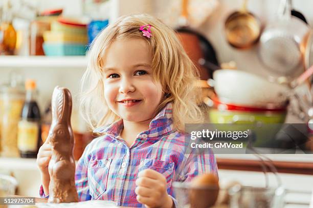 niedlich kleines mädchen essen schokolade osterhasen - osterhase schokolade stock-fotos und bilder