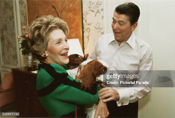 President Ronald Reagan presents First Lady, Nancy Reagan, with an early Christmas present of a king charles spaniel named Rex, at their suite in a...