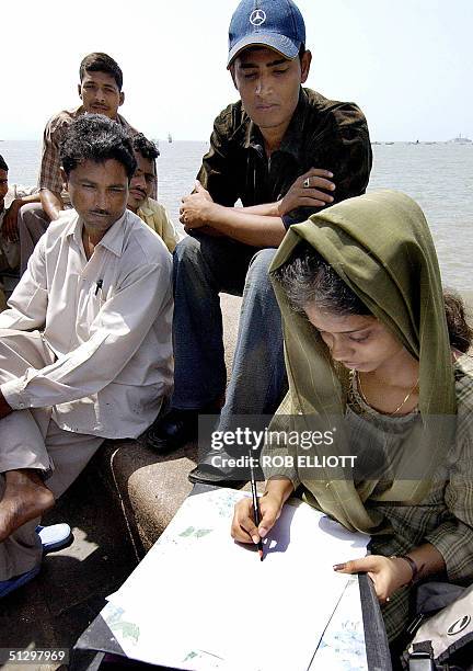 Indian men sit around and watch a female arts student as she sketches in Bombay, 13 September 2004, near the departure point for ferries going to...