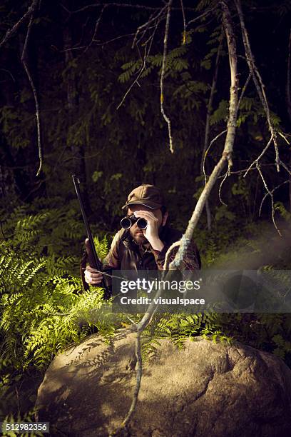 chasseur se cachent dans les buissons et à la recherche par le biais de jumelles - se cacher photos et images de collection