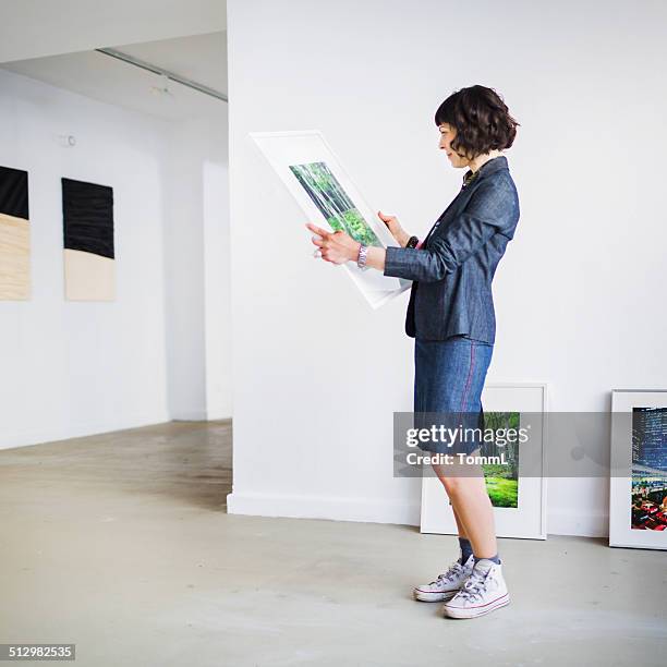 gallery owner inspecting picture - owner stand stockfoto's en -beelden