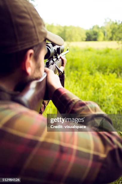 chasseur visant à proie dans le champ avec champ de tir à la carabine - lunette viseur photos et images de collection
