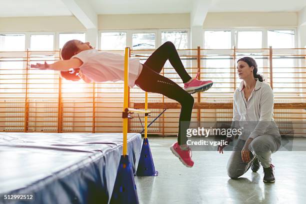 young girl practicing high jump indoors. - kids track and field stock pictures, royalty-free photos & images