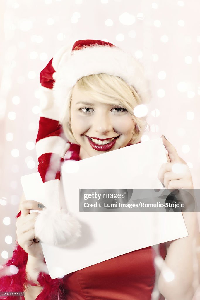 Young woman in Santa Claus costume holding empty list of wishes