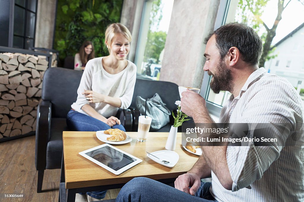 Couple dating in a cafe, man using digital tablet