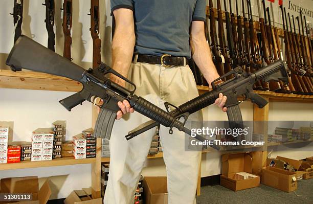 The Manager of Dave's Guns holds two Colt AR-15's, the gun on the right has a bayonet mount, flash suppressor and a collapsible stock and accepts...