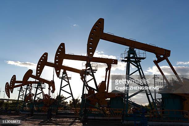 golden yellow oil rig energy industry machine oil crude in the sunset backlighting - ölfass stock-fotos und bilder