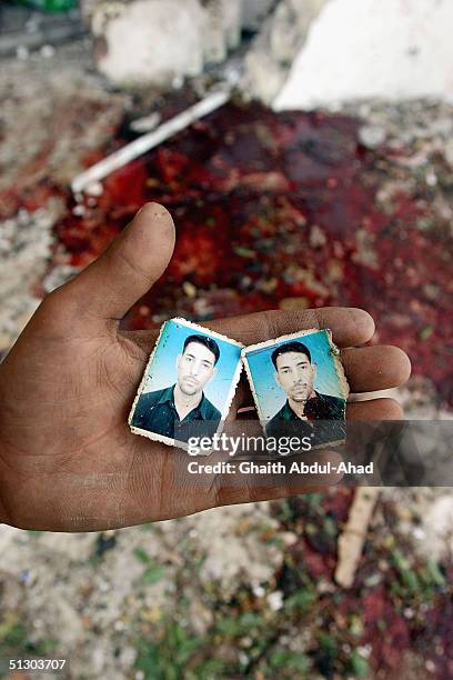 An Iraqi boy holds photographs of a new police officer who was queuing at the site of a car bomb outside the HQ of a Baghdad police station and was...