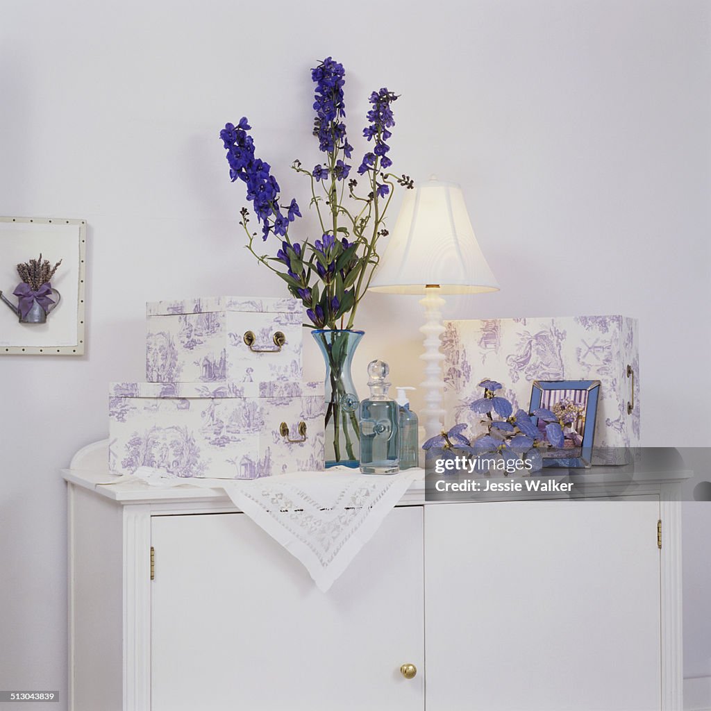 Lavender toile boxes; blue glass bottles and vase on white cabinet