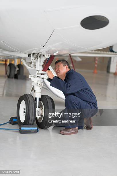 mechaniker, der das fahrwerk eines flugzeugs fixiert - landing gear stock-fotos und bilder
