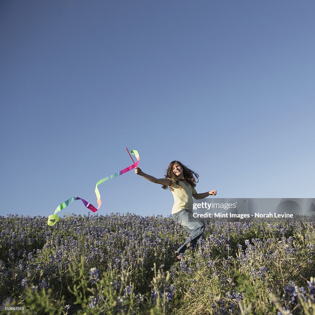 A child, a girl running with a paper streamer fluttering in the wind.