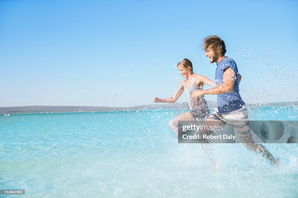 Couple running in water on beach