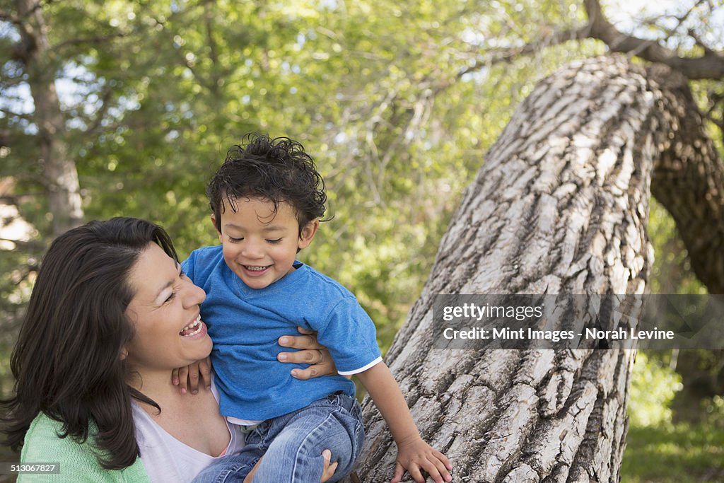 A mother and son in the park in Santa Fe, by a tall tree.