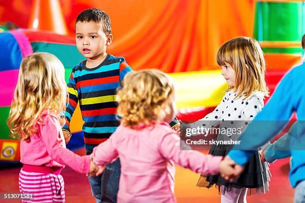 children dancing in a playroom. - hold hands circle stock pictures, royalty-free photos & images