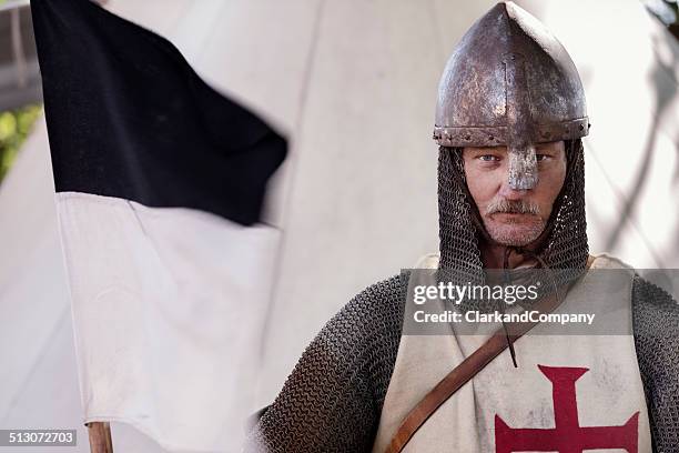 stern looking knight holding a regimental flag. - the crusades stockfoto's en -beelden