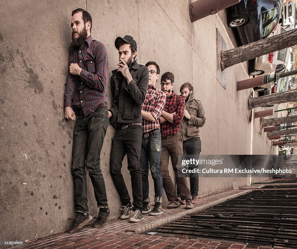 Sideway view of five young men pretending to walk along sidewalk