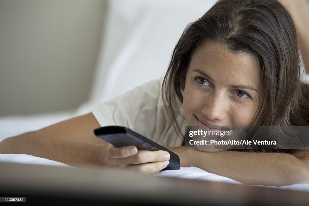 Woman lying on bed watching TV