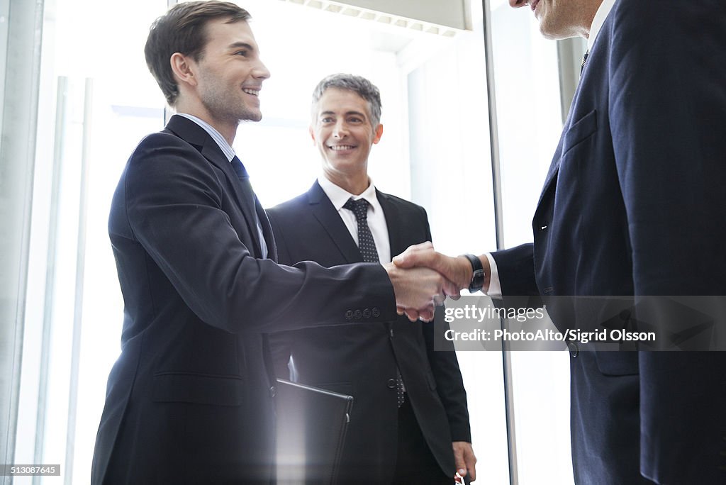 Young businessman shaking hands with senior associate