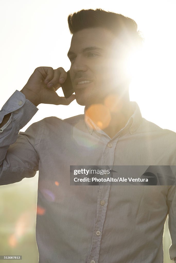 Young man talking on cell phone, silhouette