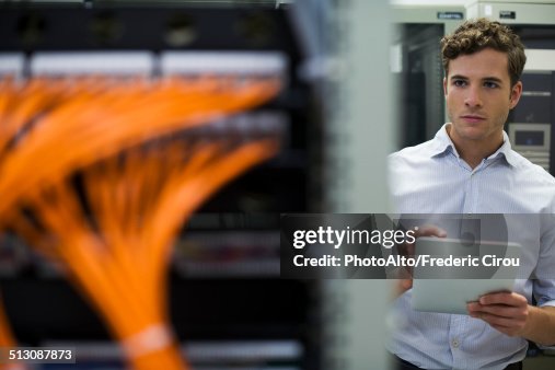 Computer technician using digital tablet performing maintenance check of mainframe equipment Computer technician using digital tablet performing maintenance check of mainframe equipment
