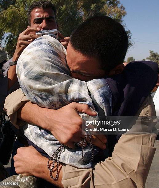 An Iraqi prisoner receives a hug from a relative after being brought by bus from Abu Ghraib prison to an Iraqi Military base in Baghdad for release...