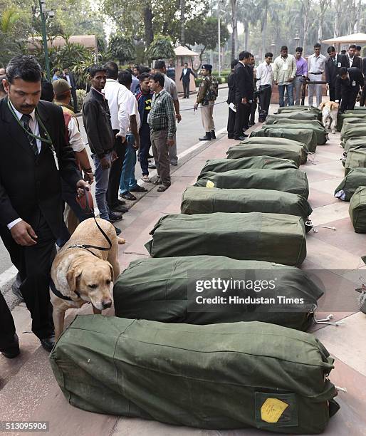 Security personnel helps special trained dogs checking the budget papers before carrying inside the Parliament during the Budget Session on February...