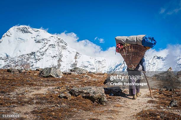 sherpa porter carrying heavy load in traditional basket himalayas nepal - sherpa stockfoto's en -beelden