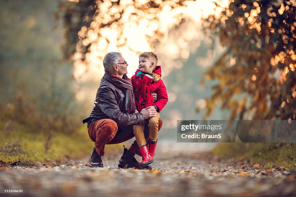 Loving grandfather and grandson talking to each other in autumn.